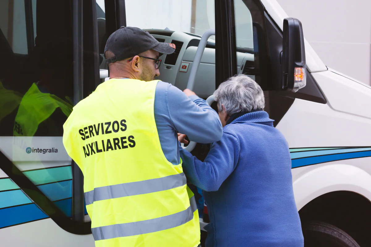 Personal acompañante ayudando a una persona a subir al vehículo de transporte